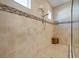 Walk-in shower featuring neutral colored tile with decorative tile accents and a teakwood corner seat at 12835 Sorrento Way, Bradenton, FL 34211