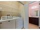 Well-equipped laundry room with side-by-side washer and dryer, shelving, and convenient access to the bathroom at 13574 Circa Crossing Dr, Lithia, FL 33547