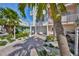 Charming townhome exterior with palm trees, a paved driveway, a one-car garage, and well-manicured landscaping at 140 Brightwater Dr # 1, Clearwater Beach, FL 33767