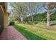 View of the lush, green backyard with mature trees and manicured landscaping at 15908 Cobble Mill Dr, Wimauma, FL 33598