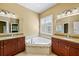 Bright bathroom features dual sinks, granite countertops, and corner soaking tub under window at 15908 Cobble Mill Dr, Wimauma, FL 33598