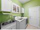 Bright laundry room with updated appliances, cabinets, and plenty of counter space at 15908 Cobble Mill Dr, Wimauma, FL 33598