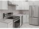 Bright kitchen featuring white cabinets, stainless steel appliances, and light countertops at 209 Ne Lincoln N Cir # 105, St Petersburg, FL 33702