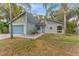 Inviting single-story home displays beautiful landscaping and a blue garage door, framed by mature palm trees at 2402 Regal Dr, Lutz, FL 33549