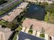 Aerial view of townhomes bordering a scenic lake with a fountain, alongside a highway with meticulously maintained landscaping at 2537 Gloriosa Dr # 2, Palm Harbor, FL 34684