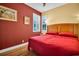 Cozy bedroom showcasing a red bedspread, natural light, and wood-look flooring at 2537 Gloriosa Dr # 2, Palm Harbor, FL 34684