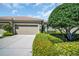 Inviting home exterior featuring a two-car garage, tiled roof, lush landscaping, and a well-maintained driveway at 2537 Gloriosa Dr # 2, Palm Harbor, FL 34684