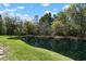 Lush green backyard with a tranquil pond reflecting the cloudy blue sky at 2747 Enterprise E Rd # 17, Clearwater, FL 33759