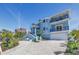 Stylish blue home with multiple balconies, a brick driveway, and a two-car garage, surrounded by lush landscaping at 289 8Th N Ave, Tierra Verde, FL 33715