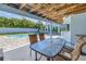 Covered outdoor patio with a glass table, wicker chairs and TV overlooking the pool at 289 8Th N Ave, Tierra Verde, FL 33715