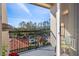 A balcony with green metal railings overlooks mature trees and a parking lot on a beautiful sunny day at 4209 Woodstorks Walk Way # 1304, Lutz, FL 33558