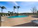 Community pool surrounded by lounge chairs and lush landscaping with lake views on a sunny day at 4209 Woodstorks Walk Way # 1304, Lutz, FL 33558