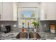 Sunlit kitchen featuring stainless steel sink, gray granite countertops, and bright subway tile backsplash at 7505 Exter Way, Tampa, FL 33615