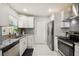 Modern kitchen featuring white cabinets, stainless appliances, granite counters, and stylish subway tile backsplash at 7505 Exter Way, Tampa, FL 33615