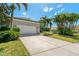 Exterior of home features an attached garage and beautiful tropical landscaping at 1006 Osprey Ct, Tarpon Springs, FL 34689