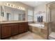 Bathroom featuring double sinks, soaking tub, glass enclosed shower and travertine tile at 11218 Coventry Grove Cir, Lithia, FL 33547