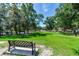 Lush park with a green lawn, mature trees, and a comfortable bench at 11218 Coventry Grove Cir, Lithia, FL 33547