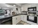 Modern kitchen view with black countertops, white cabinetry, and seamless flow to the living space at 12041 Hoosier Ct # 104, Hudson, FL 34667