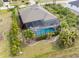 Aerial shot of a screened in pool with lounge chairs, pavers, and nice landscaping at 135 Cabana Way, Rotonda West, FL 33947