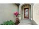 Elegant front entryway with decorative glass door, textured walls, and vibrant plants at 135 Cabana Way, Rotonda West, FL 33947