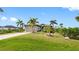 Well-maintained property featuring a lush green lawn, mature palm trees, and a paved driveway at 135 Cabana Way, Rotonda West, FL 33947