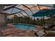 Screened pool area featuring lounge chairs and umbrella, perfect for relaxation and entertainment at 135 Cabana Way, Rotonda West, FL 33947