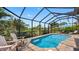Beautiful screened-in pool with comfortable loungers and lush tropical landscaping at 135 Cabana Way, Rotonda West, FL 33947