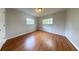 A vacant room featuring hardwood floors, two windows and neutral gray walls at 1433 S Belcher Rd # E10, Clearwater, FL 33764