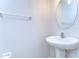 A half-bathroom with a pedestal sink and oval mirror, offering a convenient and functional space at 14477 Editors Note St, Ruskin, FL 33573
