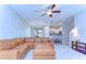 Open-concept living room featuring a tan sofa, ceiling fan, and a kitchen bar at 14477 Editors Note St, Ruskin, FL 33573
