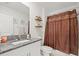 Well-lit bathroom featuring granite countertop, floating shelves, a decorative shower curtain and white cabinetry at 17950 Beaming Rays Ln, Lutz, FL 33558