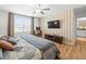 Bedroom featuring a TV, a large window, hardwood floors, and an adjacent bath at 17950 Beaming Rays Ln, Lutz, FL 33558