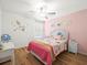Charming bedroom with hardwood floors, a ceiling fan, and playful decor on the walls at 17950 Beaming Rays Ln, Lutz, FL 33558