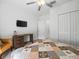 Bright bedroom with a ceiling fan, desk, TV, closet, and a stylish quilt on the bed at 17950 Beaming Rays Ln, Lutz, FL 33558