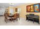 Charming dining room featuring a glass-top table, wood chairs, piano, and stylish artwork at 17950 Beaming Rays Ln, Lutz, FL 33558