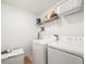 Functional laundry room is equipped with a washer, dryer, and storage shelves at 17950 Beaming Rays Ln, Lutz, FL 33558