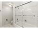 Bright bathroom featuring a glass-enclosed tiled bathtub with chrome fixtures and white walls at 19029 Us Highway 19 N # 2-17, Clearwater, FL 33764