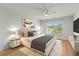 Staged bedroom features a ceiling fan, a large window, and hardwood style flooring at 19029 Us Highway 19 N # 2-17, Clearwater, FL 33764