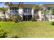 Charming condo exterior surrounded by lush, green lawn and mature palm trees providing a tropical feel at 19029 Us Highway 19 N # 2-17, Clearwater, FL 33764