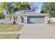 Inviting home with a well-maintained lawn, mature trees, and a spacious driveway leading to a two-car garage at 1972 Sourwood Blvd, Dunedin, FL 34698