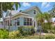 A light blue two-story home showcases a manicured lawn and charming exterior features, including many windows and palm trees at 210 15Th N Ave, St Petersburg, FL 33704