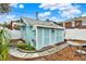 Charming blue outbuilding with a gray roof, surrounded by landscaping and a white fence at 210 15Th N Ave, St Petersburg, FL 33704