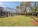 Large backyard featuring a screened pool area, mature trees, and a wooden playset at 2280 Mackenzie Ct, Clearwater, FL 33765