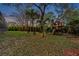 Backyard featuring a playhouse surrounded by mature trees, manicured lawn, and lush landscaping at dusk at 2280 Mackenzie Ct, Clearwater, FL 33765