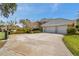 Long driveway leading to a three-car garage, complimented by mature landscaping and a basketball hoop at 2280 Mackenzie Ct, Clearwater, FL 33765