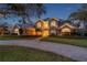 Beautiful twilight view of a grand home with a brick driveway, manicured landscaping, and a welcoming entrance at 2280 Mackenzie Ct, Clearwater, FL 33765