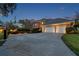 Exterior view of a home at dusk, showcasing a large driveway, three-car garage, and landscaped front yard at 2280 Mackenzie Ct, Clearwater, FL 33765