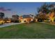 Dusk view of a well-manicured lawn and beautiful home with a three-car garage and mature trees at 2280 Mackenzie Ct, Clearwater, FL 33765