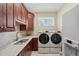 Inviting laundry room with cabinets, sink, countertop, a front loading washer and dryer, and a window at 2280 Mackenzie Ct, Clearwater, FL 33765
