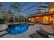 Beautiful backyard pool area at twilight, featuring lounge chairs and a covered lanai with an outdoor kitchen at 2280 Mackenzie Ct, Clearwater, FL 33765